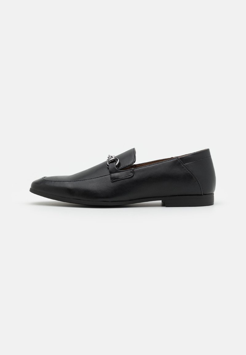 Mocassin homme en cuir noir avec détail en métal argenté, talon bas et bout arrondi, présenté de profil sur fond blanc.