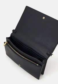 Černá kožená peněženka s texturovaným povrchem. Disponuje zlatým zipem, několika přihrádky na karty a patentním zavíráním. Interiér má hladké podšívání.