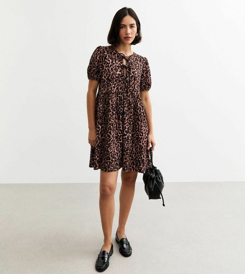 Robe à imprimé léopard avec manches bouffantes, corsage ajusté et jupe légère. Associée à des mocassins noirs et un petit sac noir.