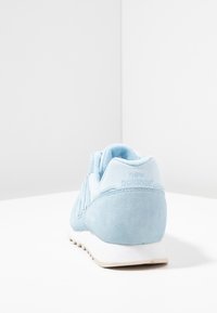 Baskets en suède bleu clair avec un col rembourré, semelle en caoutchouc et marque brodée. Elles ont un bout arrondi et des accents texturés.