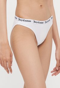 White cotton bikini underwear with a logo waistband in black, featuring a thin, minimalist design and smooth, soft texture.