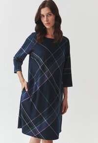 Robe navy avec motif à carreaux en vert, rose et blanc. Manches trois-quarts et poches sur les côtés. Tissu doux avec une silhouette en A.