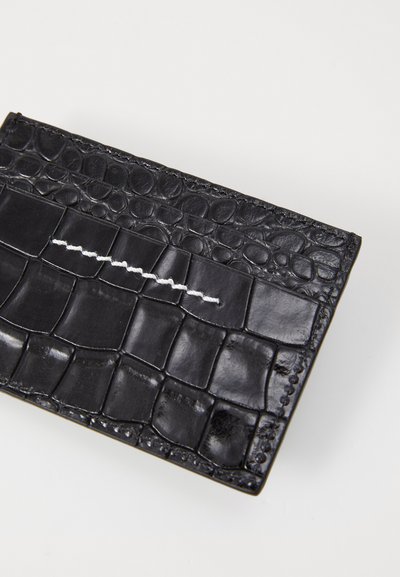Carteira de couro preto com padrão texturizado de crocodilo, apresentando um destaque em costura branca proeminente e acabamentos lisos. Forma retangular compacta.