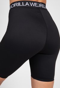 Shorts de compression noirs en matériau extensible, avec une large ceinture élastique portant la marque "GORILLA WEDGIE" et une finition lisse.