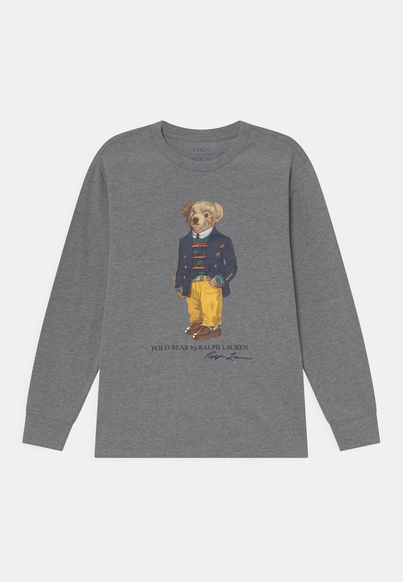 T-shirt grigio a maniche lunghe con una stampa fantasiosa di un orso vestito con un blazer blu, una camicia a righe, pantaloni gialli e scarpe marroni.