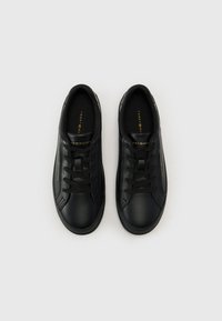 Baskets noires en cuir lisse, dotées d'un bout rond, d'un laçage à l'avant, d'une semelle intérieure rembourrée et d'un marquage subtil en or.