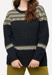 Stickad marinblå tröja med texturerat mönster, som har en flerfärgad geometrisk design i nyanser av grön, krämfärgad och svart längs oket och ärmarna.