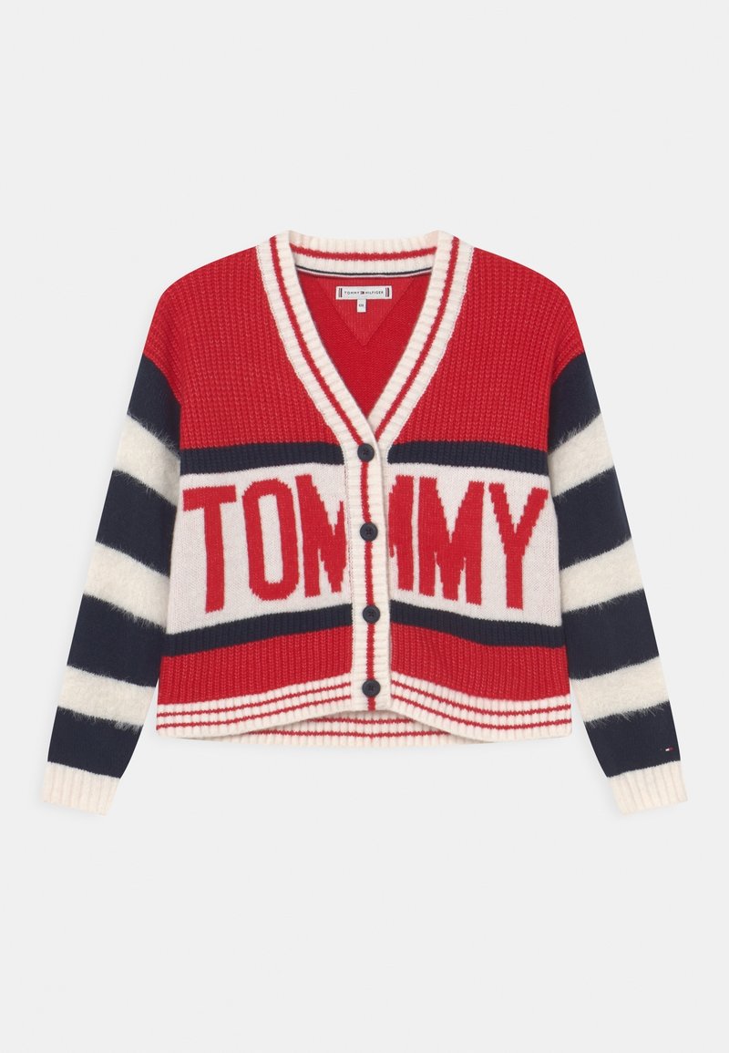 Czerwony i granatowy sweter z dzianiny z białymi paskami, z dekoltem w serek, zapięciem na guziki oraz dużym napisem "TOMMY" na klatce piersiowej.