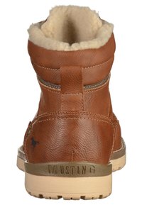 Brun läderankelhatt med beige fleecefoder, gummisula, dragflik och "MUSTANG" präglat på hälen.