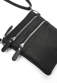 Schwarze Leder-Crossbody-Tasche mit drei Reißverschlussfächern, strukturierten Oberflächen und silbernen Hardware-Elementen. Verstellbarer Träger enthalten.