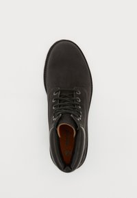 Mustad mustad nahast ankle kingad, millel on ümar varvas, sidumisüsteem, pehmendusega krae ja oranž sisevooder. Sile tekstuur ja minimalistik disain.