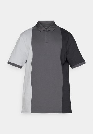 Polo a maniche corte in una sfumatura di grigio chiaro a grigio scuro. Realizzato in tessuto morbido con colletto tradizionale e tre bottoni.