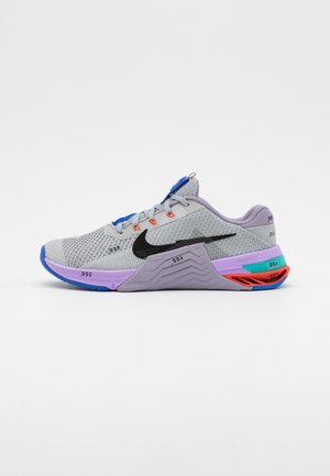 Lysegrå Nike løbesko med sort swoosh, lilla mellemsål, blå og orange detaljer samt åndbart mesh-øverst set fra siden.