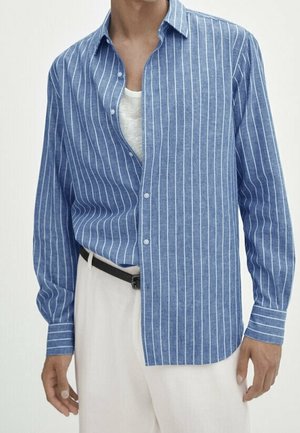 Man draagt een blauw-wit verticaal gestreept overhemd met knopen over een wit ondershirt, gecombineerd met witte broek en een zwarte riem.