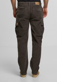 Brązowe kordurowe spodnie cargo o slim fit, z dwoma bocznymi kieszeniami i teksturowaną powierzchnią. Z tyłu naszywka z nazwą marki.