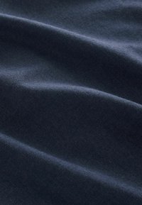 Tissu bleu foncé doux avec des plis légers et une texture lisse, mettant en valeur son tissage uniforme et son éclat subtil.
