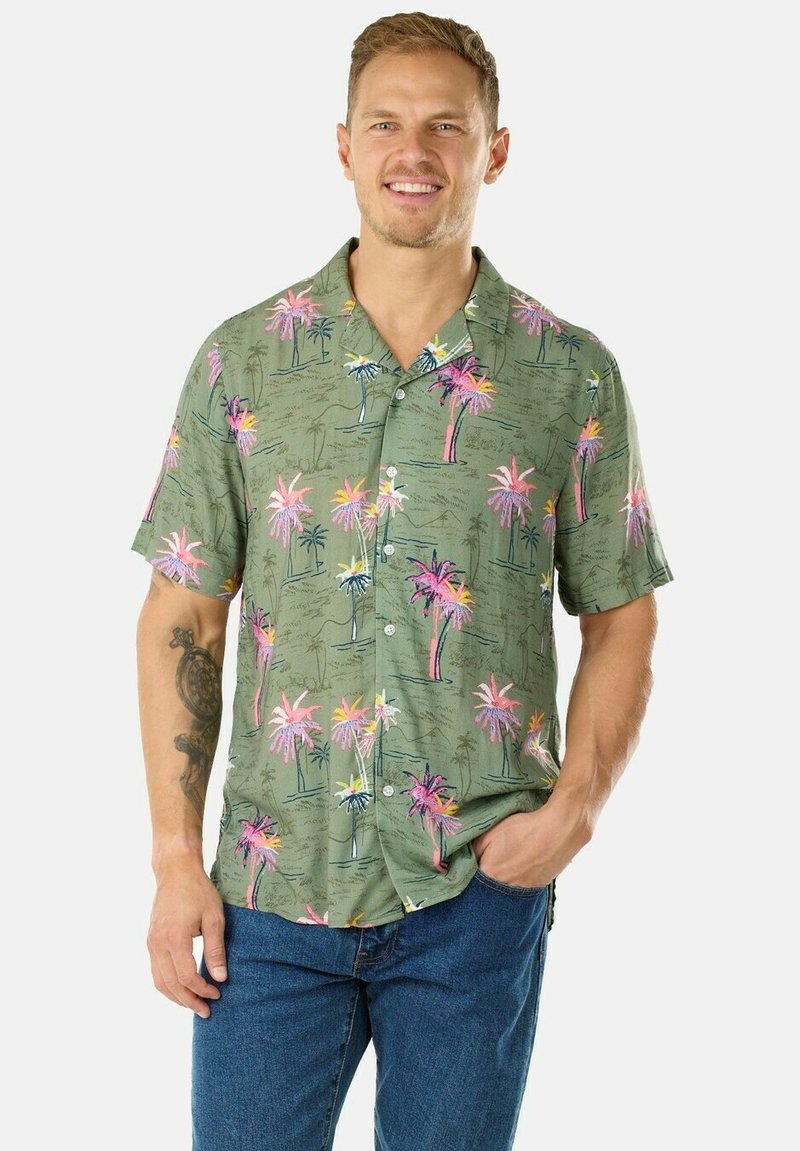 Camicetta verde a maniche corte con stampa di palme in rosa, viola e bianco. Tessuto leggero, design con bottoni, vestibilità rilassata. Indossati jeans di denim.