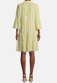 Żółta sukienka z nadrukiem w panterkę, rękawami o długości ¾, warstwową spódnicą i delikatną teksturą. Wykończona okrągłym dekoltem.