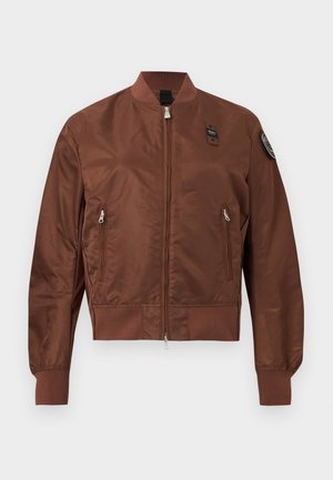 Giacca bomber marrone con cerniera frontale, due tasche con zip, polsini e orlo a coste, e una toppa sulla parte superiore della manica sinistra.