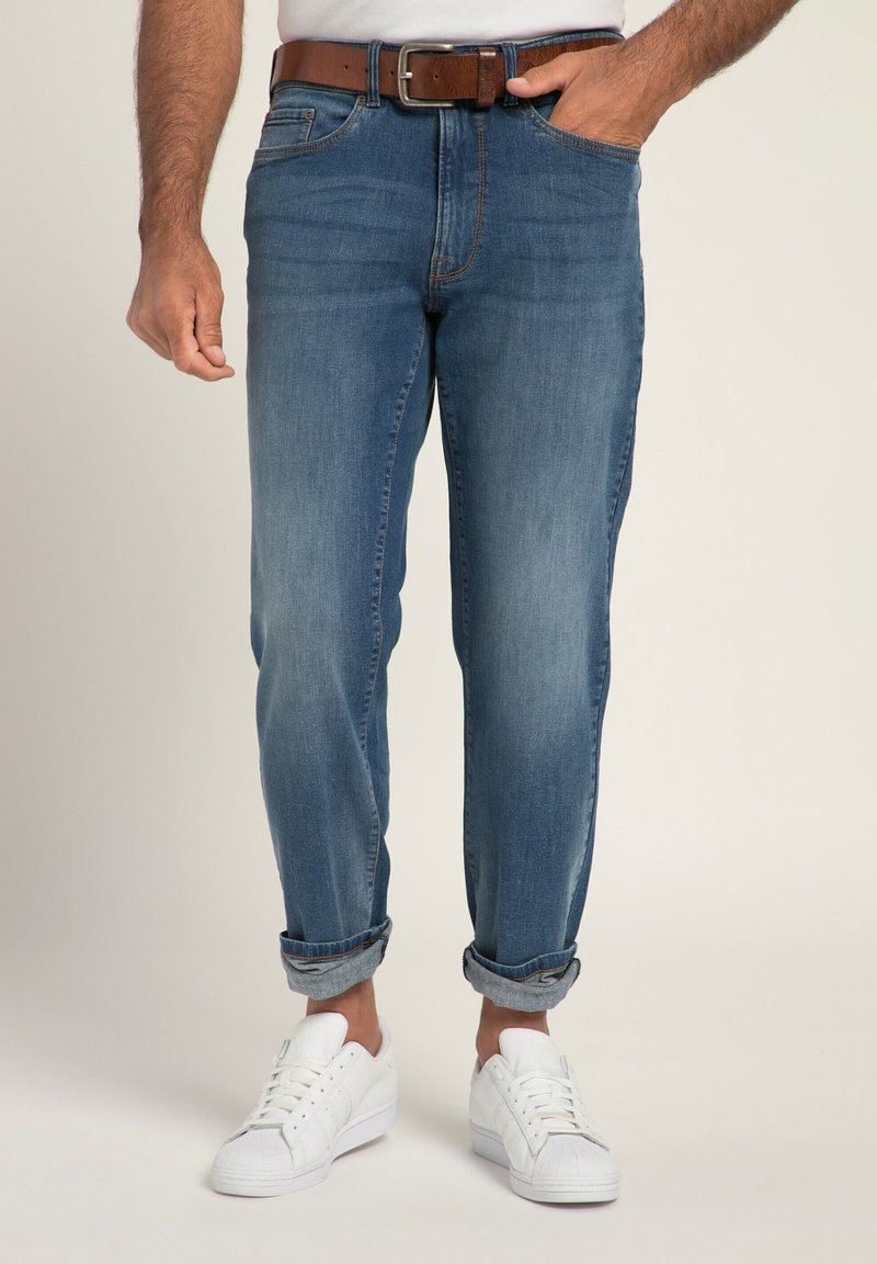 Jeans de denim azul claro con un corte relajado, puños enrollados y un cinturón de cuero marrón. Combinados con zapatillas blancas, exhibidos sobre un fondo neutro.