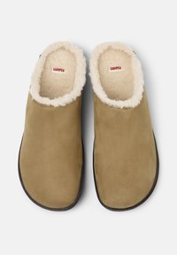 Pantofole in suede marrone senza lacci con un morbido rivestimento in crema. Forma della punta arrotondata e suola in gomma nera. L'etichetta interna recita "CAMPPER."