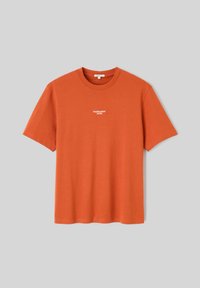 T-shirt orange en coton à manches courtes avec un petit texte blanc "TEMPÉRAMENT DE FEU" centré sur la poitrine sur un fond gris.