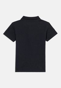 Μαύρο πόλο πουκάμισο με γιακά, κοντά μανίκια και υφασμένο ύφασμα. Η πλάτη είναι απλή με μια μικρή ετικέτα στον λαιμό.