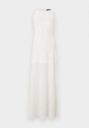 Robe maxi blanche sans manches avec corsage texturé et jupe fluide lisse, col rond, suspendue devant un fond blanc.