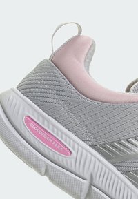Baskets de sport grises avec une finition texturée, accents roses au niveau du talon et une semelle blanche. Présente la marque "CLOUDFOAM FLEX" en rose.