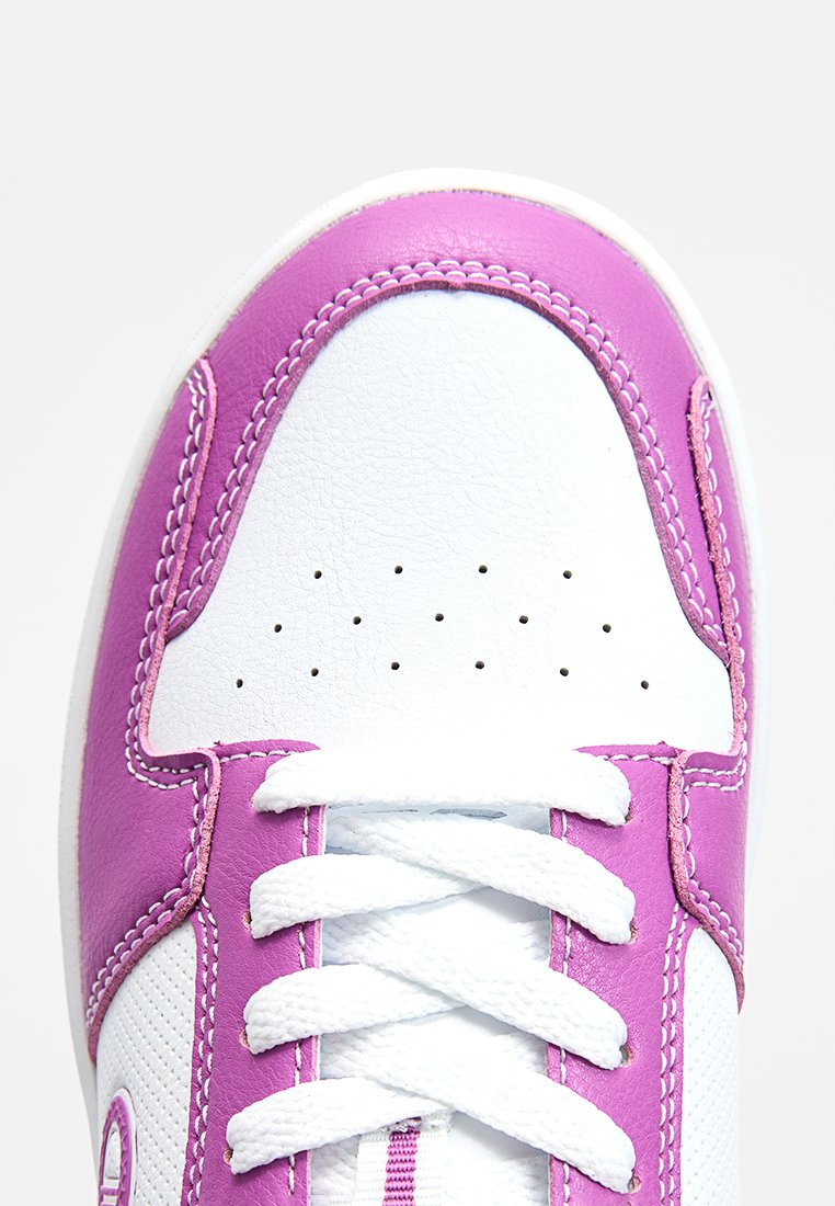 Baskets blanches avec des accents violets, tige synthétique lisse, zone de orteils perforée et lacets texturés. Le surfilage le long des bords est bien visible.