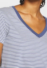 Vit T-shirt med V-ringning och blå horisontella ränder, med korta ärmar och en-texturerad tyg för komfort.