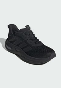 Black athletic shoe with a breathable knitted upper, mesh accents, and thick rubber sole. Features soft laces and three stripe branding.