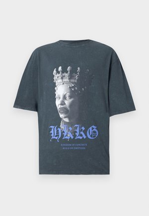 T-shirt noire oversized avec un graphique d'une sculpture de tête couronnée. Le texte en dessous indique "HKKG" et "KINGDOM OF CONCRETE BUILD ON EMOTIONS."