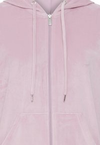 Lyserød velour zip-up hoodie med en frontlynlås, snore og to forlommer. Blød tekstur med en glat finish.