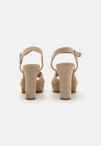 Beige suède hoge hakken sandalen met een ronde neus, open achterkant en enkelbandje. Opvallende blokhak en minimalistisch ontwerp.