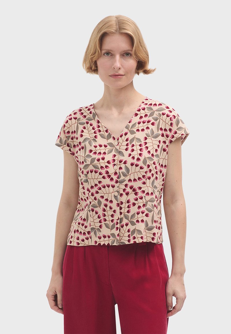 Blusa a maniche corte in tessuto beige con motivi floreali rossi e foglie verdi, dotata di scollo a V e vestibilità comoda.