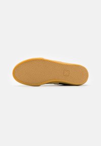 Sola de sapato de borracha com底 amarelo texturizado. Apresenta um logótipo no centro e uma borda reforçada para durabilidade.