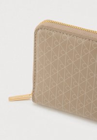 Μπεζ πορτοφόλι με φερμουάρ από υλικό με υφή, διακοσμημένο με διαμάντι σχέδιο μικρών καρδιών και χρυσά μεταλλικά στοιχεία στο φερμουάρ.