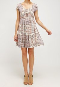 Robe légère à motifs avec manches courtes type cap, corsage ajusté et jupe évasée. Couleurs comprenant mauve, crème et tons terreux.