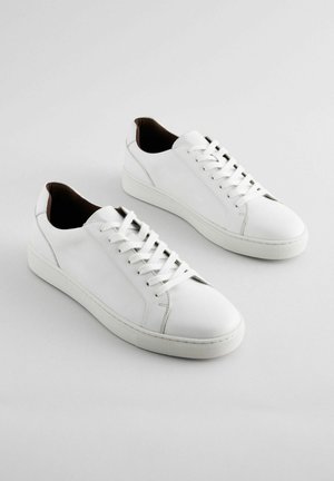 Weiße Sneaker aus glattem Leder, mit runder Spitze, Schnürung vorne und minimalistischem Design mit braunen Akzenten an der Ferse.