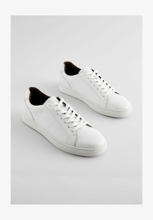 Sneakers bianchi realizzati in pelle liscia, con punta rotonda, chiusura con lacci e design minimalista con dettagli marroni sul tallone.