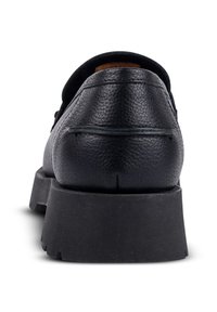 Black leather shoe with a textured finish, featuring a solid black platform sole. The design includes a rounded back and minimal stitching details.