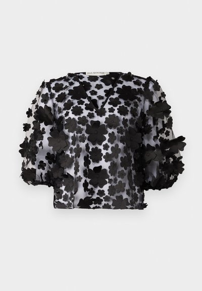 Blouse noire transparente avec un col en V et des manches bouffantes, ornée d'appliqués floraux en couches. Tissu léger et texturé avec un aspect translucide.