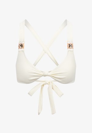 Valkoinen bikinitoppi, jossa on kolmion muotoiset kupit, säädettävät hihnat ristiin selässä ja koristeellinen kultainen yksityiskohta jalokivillä olkapäillä.