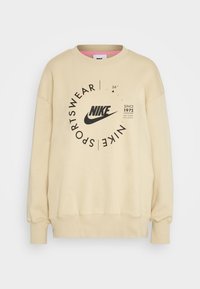 Krämfärgad Nike sweatshirt med rund logotryck, drop shoulders, ribbad mudd och fåll, med en mjuk textur.