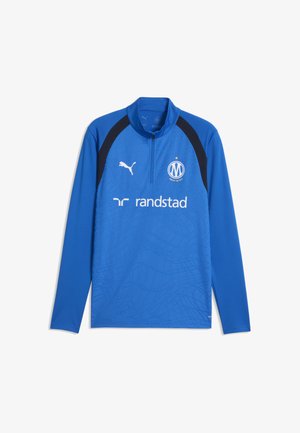 Niebieski sportowy top z długim rękawem z czarnymi panelami na ramionach, logo Puma, sponsorem Randstad oraz herbem klubu piłkarskiego Marsylia z przodu.