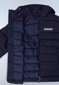 Marinblå puffjacka med en kviltad design, glänsande foder, dragkedjsstängning och logotyp på bröstet. Har en huva och en mjuk tygkänsla.