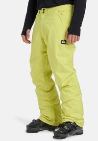 Felgekleurde gele skibroek van waterdicht materiaal, met een relaxte pasvorm, twee knopen bij de taille en een logo patch aan de zijkant.
