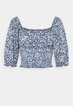 Blusa floreale blu con scollatura quadrata, maniche a sbuffo e busto arricciato. Presenta piccoli fiori bianchi e blu su sfondo blu navy.