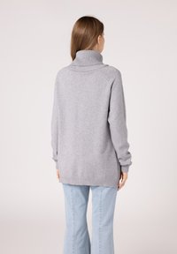 Szary, oversize sweter z wysokim ściągaczem, rękawami raglanowymi i okrągłym dołem. Miękka tekstura z bocznymi rozcięciami dla wygody.